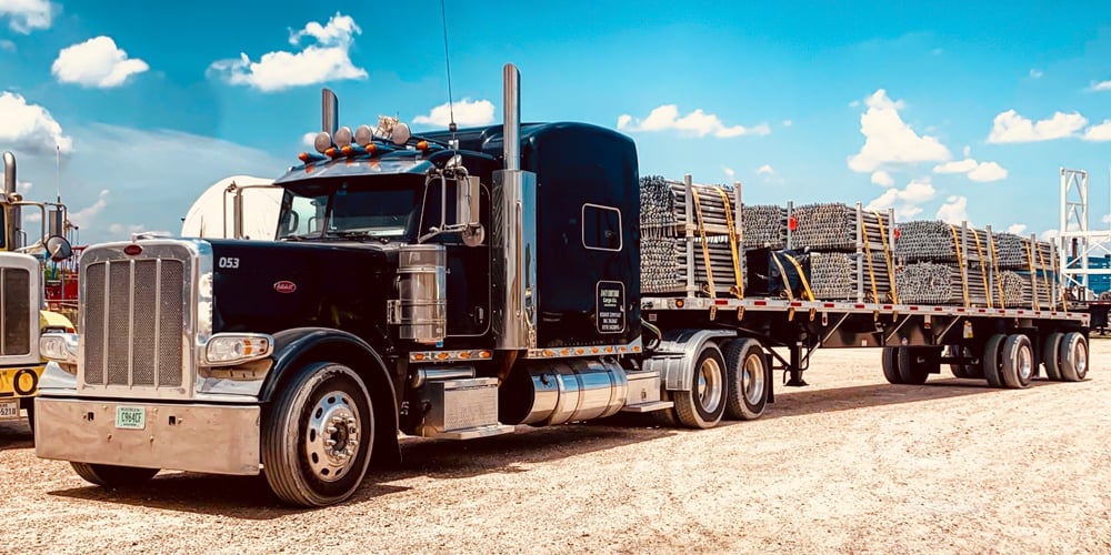 Black Peterbilt truck pulling a flatbed load